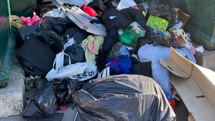 Basura acumulada entre contenedores de reciclaje